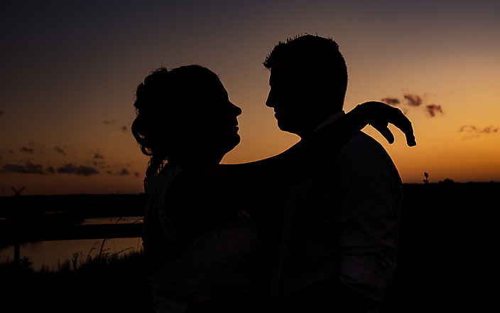 Bride and Groom silhouette at sunset yellow sky in the Netherlands by Wedding Photographer Stefan van Beek